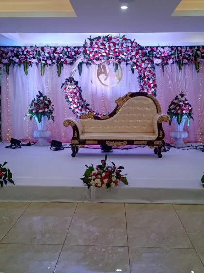 A beautiful reception stage with a broken arch design. The pink and white flowers against the light drapes, along with the ornate diwan, create a very stylish look.