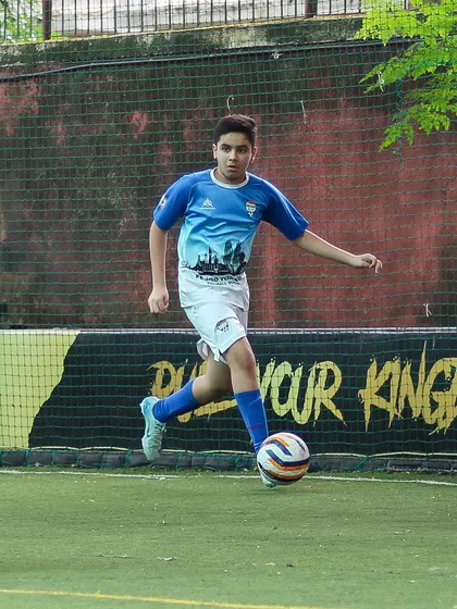 An older youth player in full stride, demonstrating powerful and controlled dribbling during a competitive match.