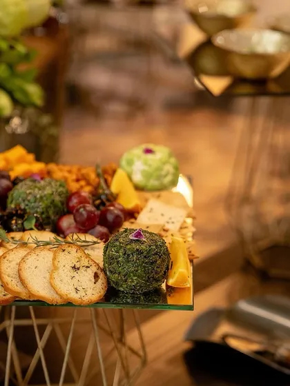 A close-up of our artisanal cheese balls, one coated in herbs and another in nuts, part of the elaborate cheese board.