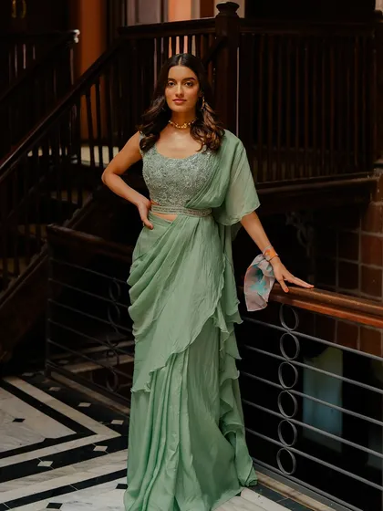 A sophisticated sage green draped saree with an embellished blouse, a modern and elegant choice for a cocktail party.