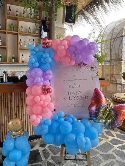 A welcome sign for Neha's baby shower, with a balloon arrangement and a large butterfly foil balloon.