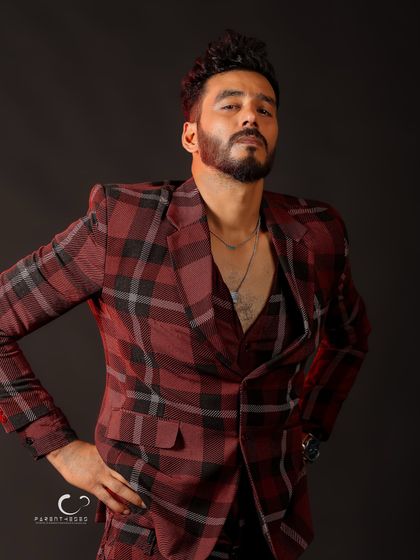 A powerful pose with hands on hips. The three-piece plaid suit makes a bold fashion statement, and his expression conveys pure confidence.