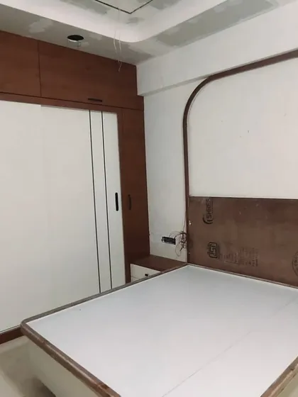 A work-in-progress shot of a bedroom, showing the basic structure of the bed with its arched headboard and the sliding wardrobe.