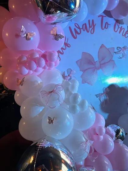 A close-up of the balloon decor for the half-birthday party, featuring delicate butterfly stickers and ribbon details on the pink and white balloons.