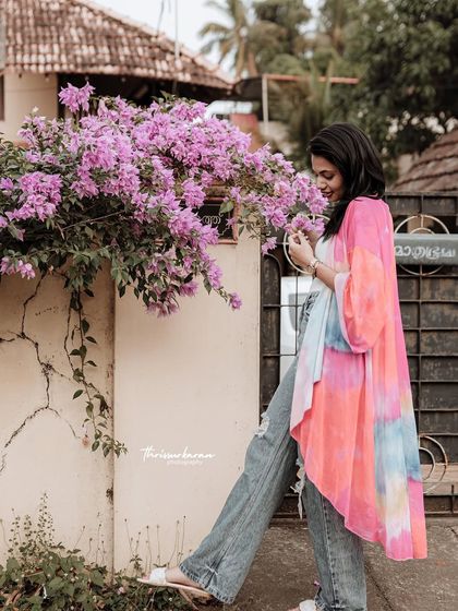 A colorful and vibrant lifestyle shot. The bright pink flowers and the model's tie-dye kimono create a cheerful and eye-catching image.