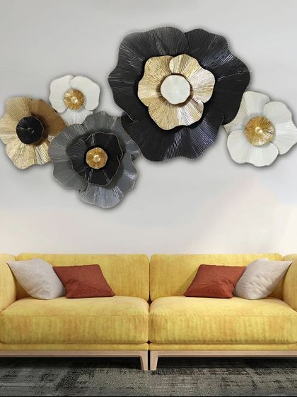 A beautiful cluster of metal flowers in black, white, grey, and gold. This large metal wall art piece is perfect for creating a dramatic and artistic focal point above a sofa.
