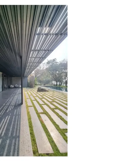 The play of light and shadow under a pergola at the Lakeshore house. The black metal grid and stone pavers interspersed with grass blur the line between the built and the natural.