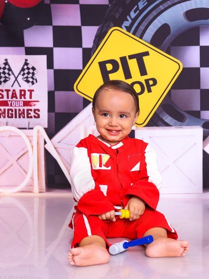 This little racer is all smiles at the pit stop. The checkered flag background and racing suit create a fun and high-energy theme.