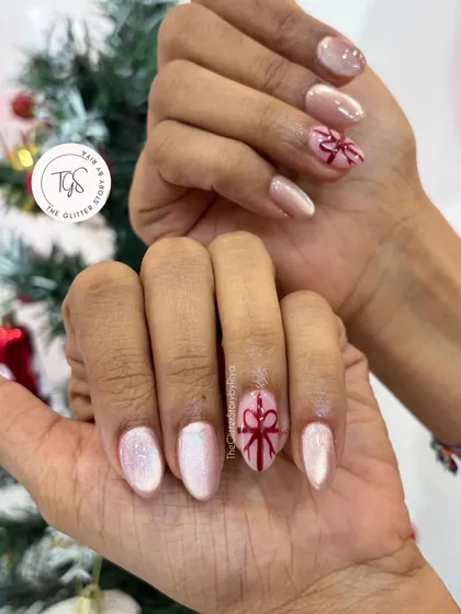 A soft and sweet holiday manicure. This set features a pearlescent pink base with a single, perfectly hand-painted red bow on each hand.