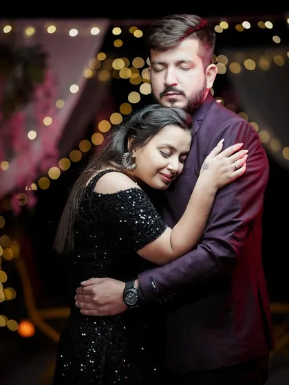 An intimate embrace during a night-time pre-wedding shoot, with the warm glow of string lights creating a romantic atmosphere.