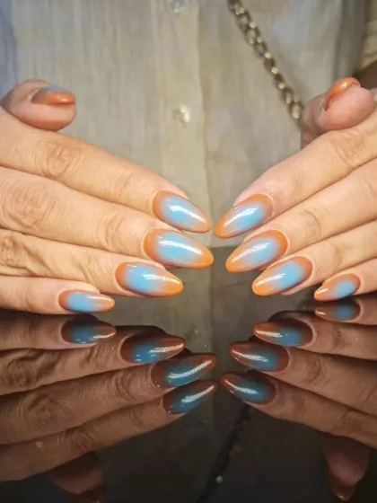 A unique and artistic design featuring a two-toned effect with blue and orange on sharp stiletto nails.