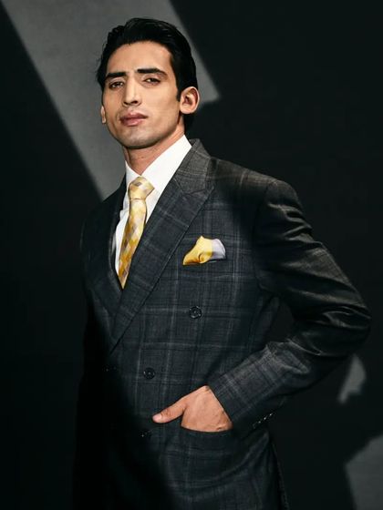 Style up your evenings with this classic double-breasted suit in a dark grey check woollen fabric, perfectly matched with a yellow tie.