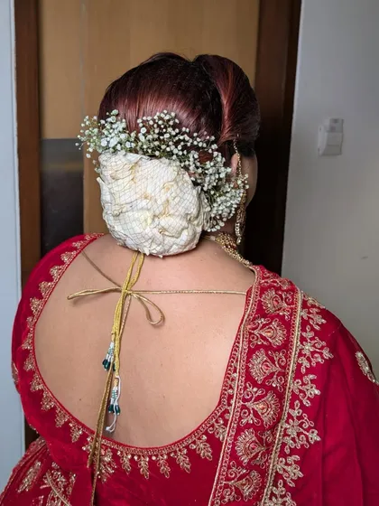 A traditional bridal bun for Shreyoshi's anniversary look. The bun is covered with a decorative net and surrounded by baby's breath for a classic touch.