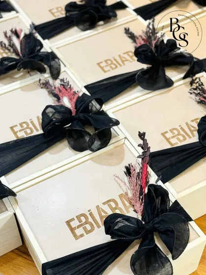 Custom wooden boxes created for a client. The brand's name is engraved on the lid, and the box is finished with a dramatic black organza bow and dried floral accents for a touch of dark romance.