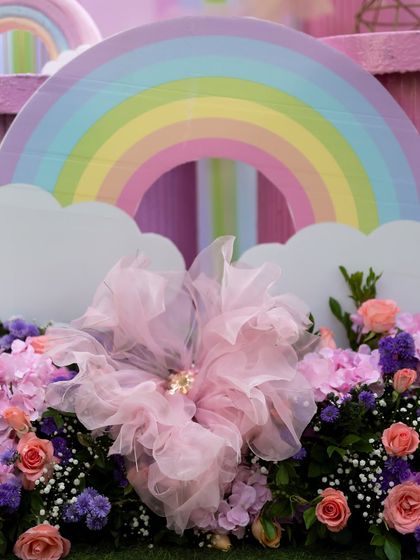 A close-up of a pastel rainbow prop and a large pink floral decoration from Ayra's party.