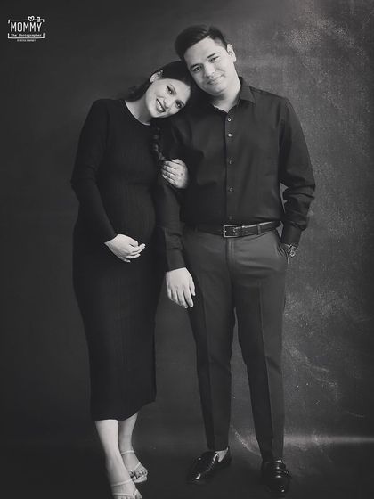 A timeless black and white portrait of the expecting couple. The simplicity of the dark backdrop and matching outfits puts all the focus on their happy connection.