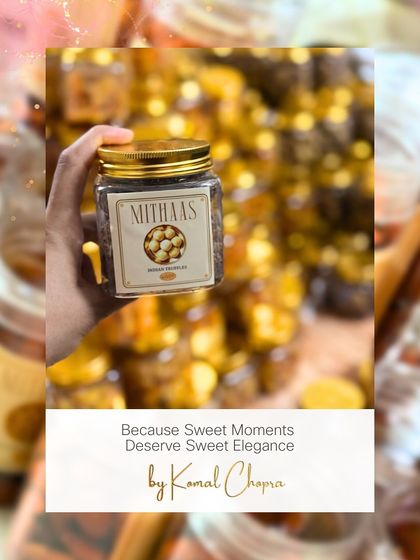 Sweet moments deserve sweet elegance. A hand holds up a jar of my gourmet wedding truffles, with stacks of gift jars blurred in the background, ready for a grand celebration.