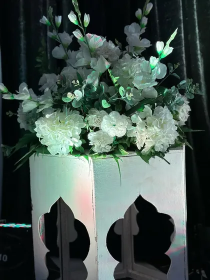 A simple yet elegant detail shot of a white floral arrangement in a custom-cut pedestal, illuminated by spotlights.