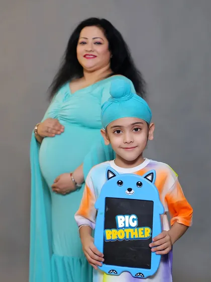 A proud "BIG BROTHER" poses with a cute sign in front of his expectant mother during their family maternity session in our studio.