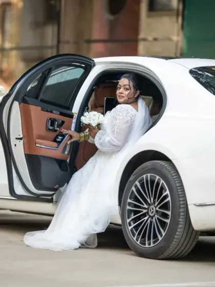 A grand entrance for a stunning bride. Stepping out of a luxury car, she looks every bit the modern princess on her wedding day.