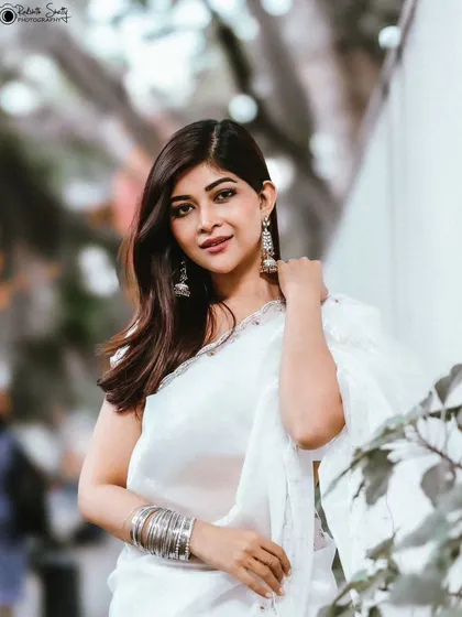 Simplicity can be incredibly powerful. This outdoor portrait captures a serene and elegant moment, with the soft white saree and silver bangles creating a beautiful contrast against the urban backdrop for a timeless look.