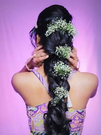 A back view of the model's hairstyle, featuring a beautiful braid adorned with baby's breath flowers.
