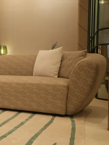 This custom sofa features a gently curved frame upholstered in a textured taupe fabric, creating a warm and inviting centerpiece. Paired with a simple off-white cushion, it showcases our ability to create comfortable, modern seating that is rich in texture.