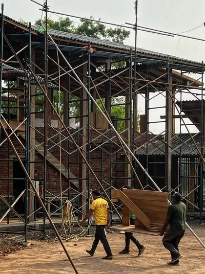 The full-scale staircase model is carried across the construction site. This process of building large-scale mock-ups allows us to test and refine complex elements before final construction begins.