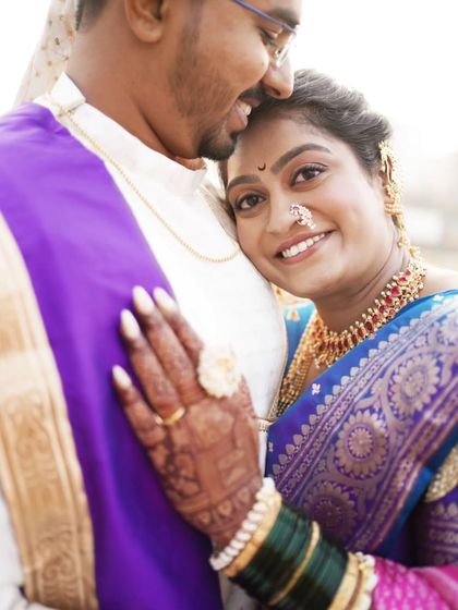 A close-up portrait capturing the bride's radiant smile as she rests her head on her groom's shoulder.