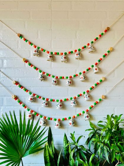 Another look at our 'Khanak' beaded bell bunting, this time in a vibrant orange and green combination. The 30-inch bunting with five mini ceramic bells is perfect for adding positive energy to your entrance.