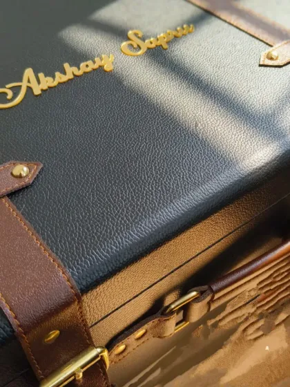 This close-up shows the detail on a personalized leatherette trunk, part of a large order for a 20-year partnership celebration between Axis Bank and Yes Bank. Each trunk was customized with the recipient's name in gold, making it a truly memorable milestone gift.