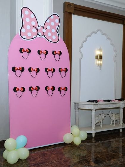 An interactive party favor display for a Minnie Mouse theme. We created a custom pink board shaped like Minnie's silhouette to hold themed headbands for the guests.
