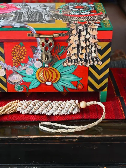A close-up of the front of the Banjara box, showing the intricate details of the painted jewelry, including jhumkas and coin tassels. It’s a celebration of tribal adornment.