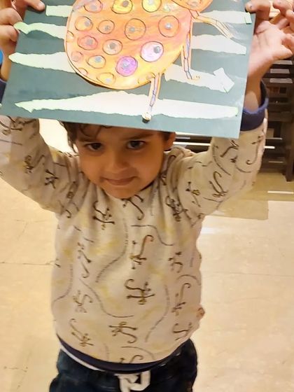 Hoisting his artwork high! This little one is thrilled with his finished ladybug project.