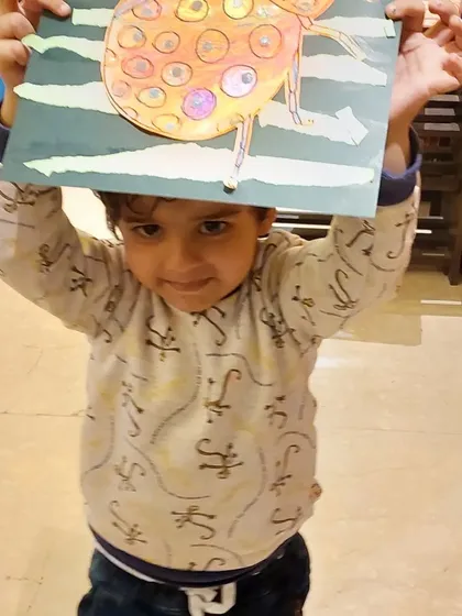 Hoisting his artwork high! This little one is thrilled with his finished ladybug project.