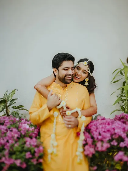 A joyful and candid portrait of the couple, with the bride hugging the groom from behind, both smiling happily.