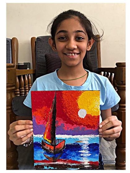 The talented artist holding her vibrant sunset boat knife painting. She has masterfully used the palette knife to create a piece full of life.