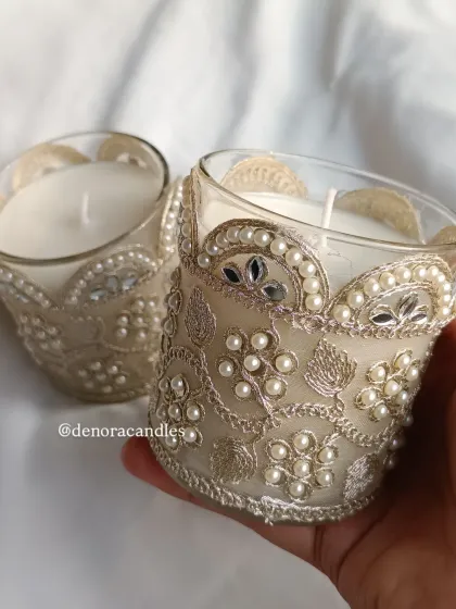 This decorative scented jar candle is wrapped in an exquisite embroidered sleeve with pearl and mirror work. It's a perfect fusion of traditional Indian craftsmanship and modern home fragrance.