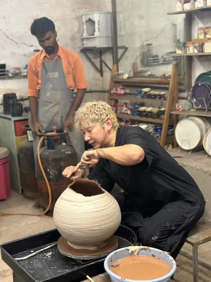 Master potter Kazuya Ishida carving the rim of a large, freshly thrown pot, with one of our studio assistants looking on.