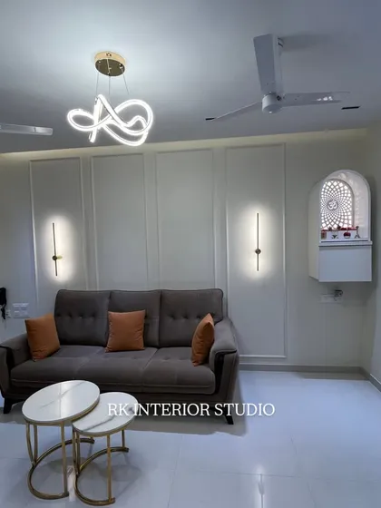 A clean and modern living room with a comfortable L-shaped sofa. I added a wall-mounted mandir and used simple wall panels and slim wall lights to create a minimalist yet elegant look.