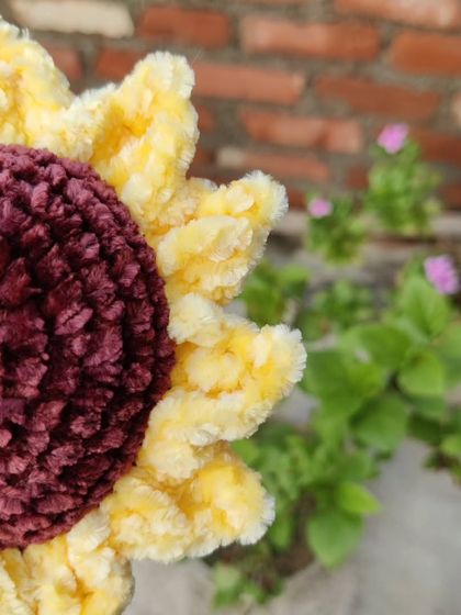 A close-up, side-angle shot of the plush sunflower, showing the texture of the yarn.
