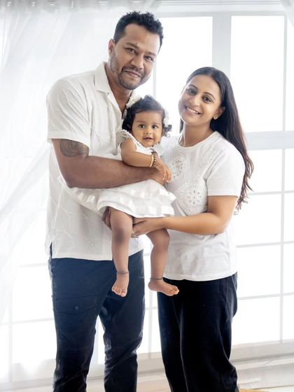 A classic family portrait, with the parents holding their daughter. A timeless photo to cherish.