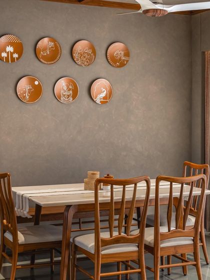 The dining area is adorned with a collection of decorative copper plates, adding a touch of traditional Indian craft to the modern space.