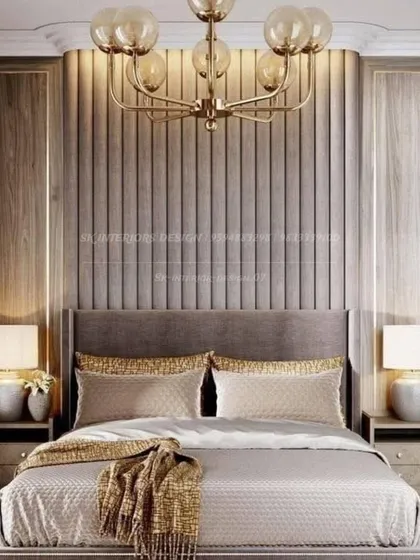 A classic and elegant bedroom with a fluted, upholstered headboard wall framed by wood panels. The warm lighting and gold accents create a cozy and inviting atmosphere.