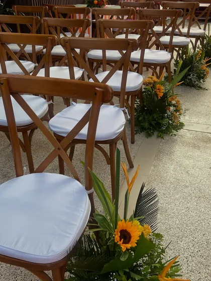 The guest seating area, with wooden cross-back chairs and aisle markers made of tropical flowers and sunflowers.