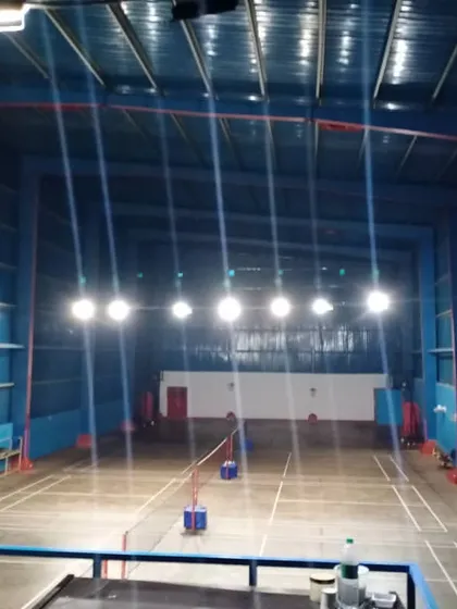 A clear view of our well-maintained, empty badminton courts. This image showcases the professional line markings, high ceilings, and powerful overhead lighting system that ensure optimal playing conditions at any time of day.
