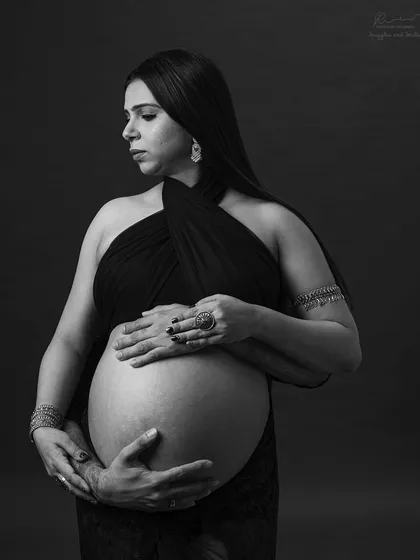 Two pairs of hands cradling the bump. This close-up shot in black and white emphasizes the shared love and anticipation of both parents.