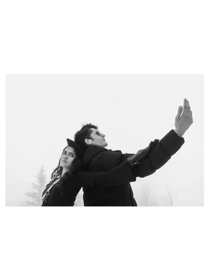 An artistic, high-contrast black and white photo with a minimalist composition. The couple's pose against the stark white snow creates a dramatic and memorable image that is both modern and timeless.