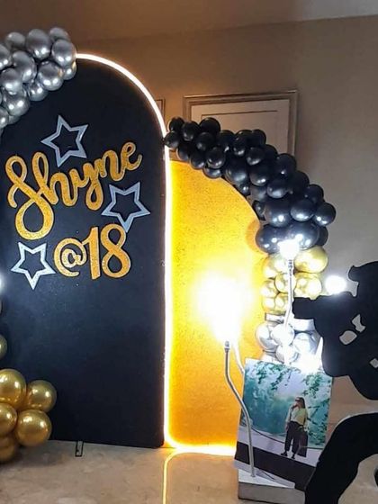 A personalized 18th birthday photo backdrop in black and gold, with a unique silhouette prop of a photographer.