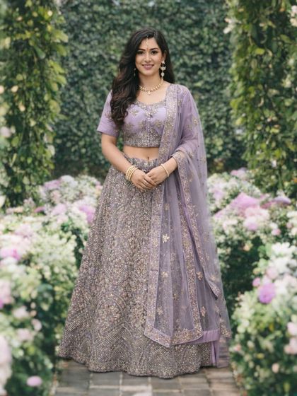 This lavender lehenga, set against a beautiful floral backdrop, looks absolutely dreamy. The rich silver embroidery on the skirt and blouse makes it a luxurious choice for any wedding event.